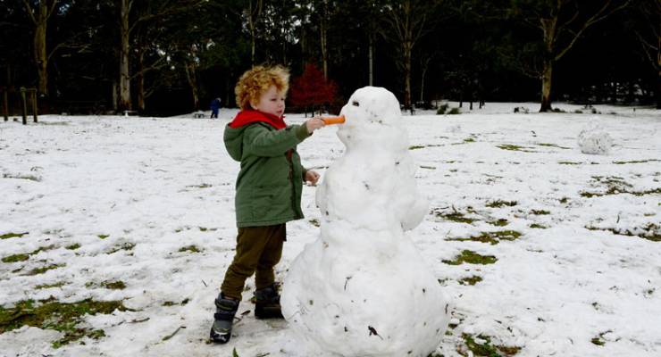 A child makes a snowman in Mt Macedon, Victoria