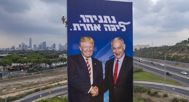 A worker hangs an election campaign billboard for Benjamin Netanyahu's Likud Party.