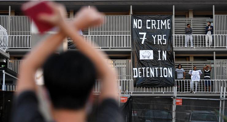 banner draped from hotel balcony protesting immigration detention