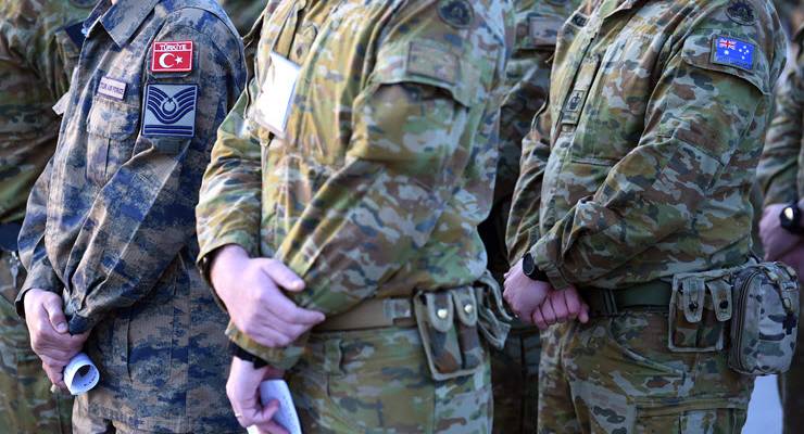 soldiers in fatigues stand with hands folded