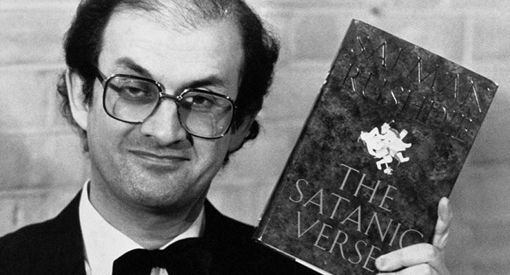 Author Salman Rushdie holding his book 'The Satanic Verses', 1989 (Image: AAP/Adam Butler/PA Wire)