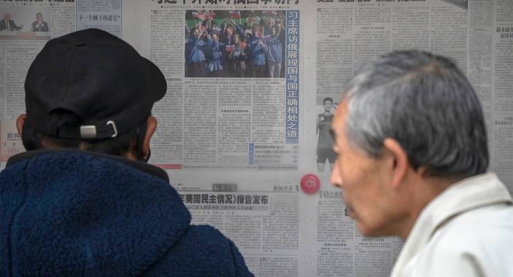 People look at a copy of the Global Times in Beijing, 2023 (Image: AAP/AP/Mark Schiefelbein)