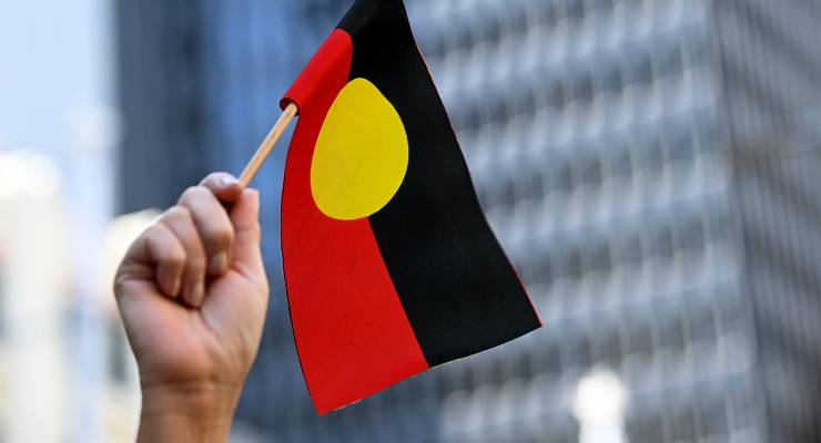 A protester waves an Aboriginal flag (Image: AAP/Bianca De Marchi)