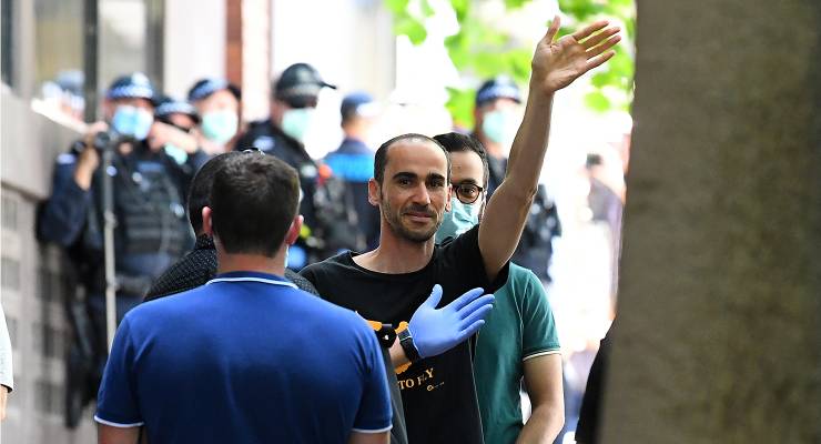 Mostafa Azimitabar gestures before entering a bus outside of the Park Hotel in Melbourne, 2021 (Image: AAP/James Ross)