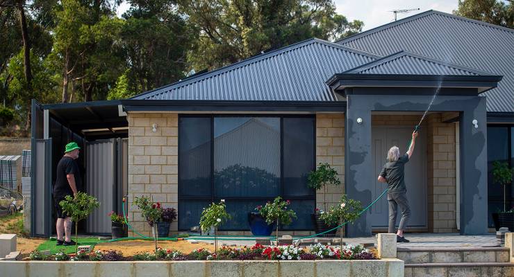 A resident wets their house ahead of an approaching fire-front in Wanneroo, Perth (Image: AAP/Aaron Bunch)